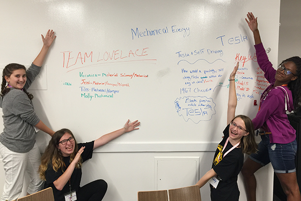 4 female students pointing at whiteboard