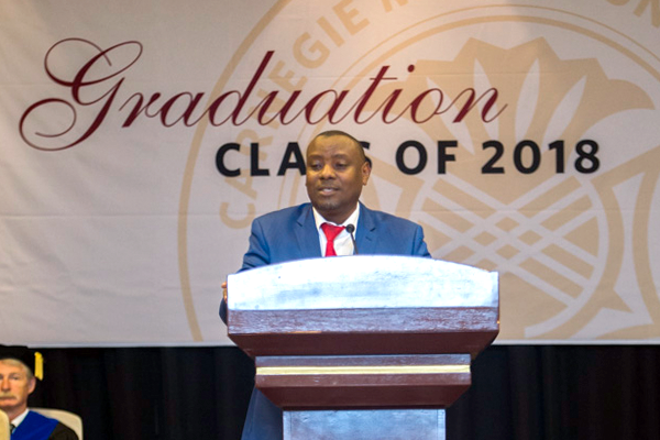 Hon. Isaac Munyakazi speaking at podium at graduation