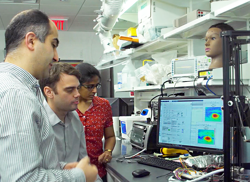 Maysam Chamanzer and two students in the lab looking at a computer screen