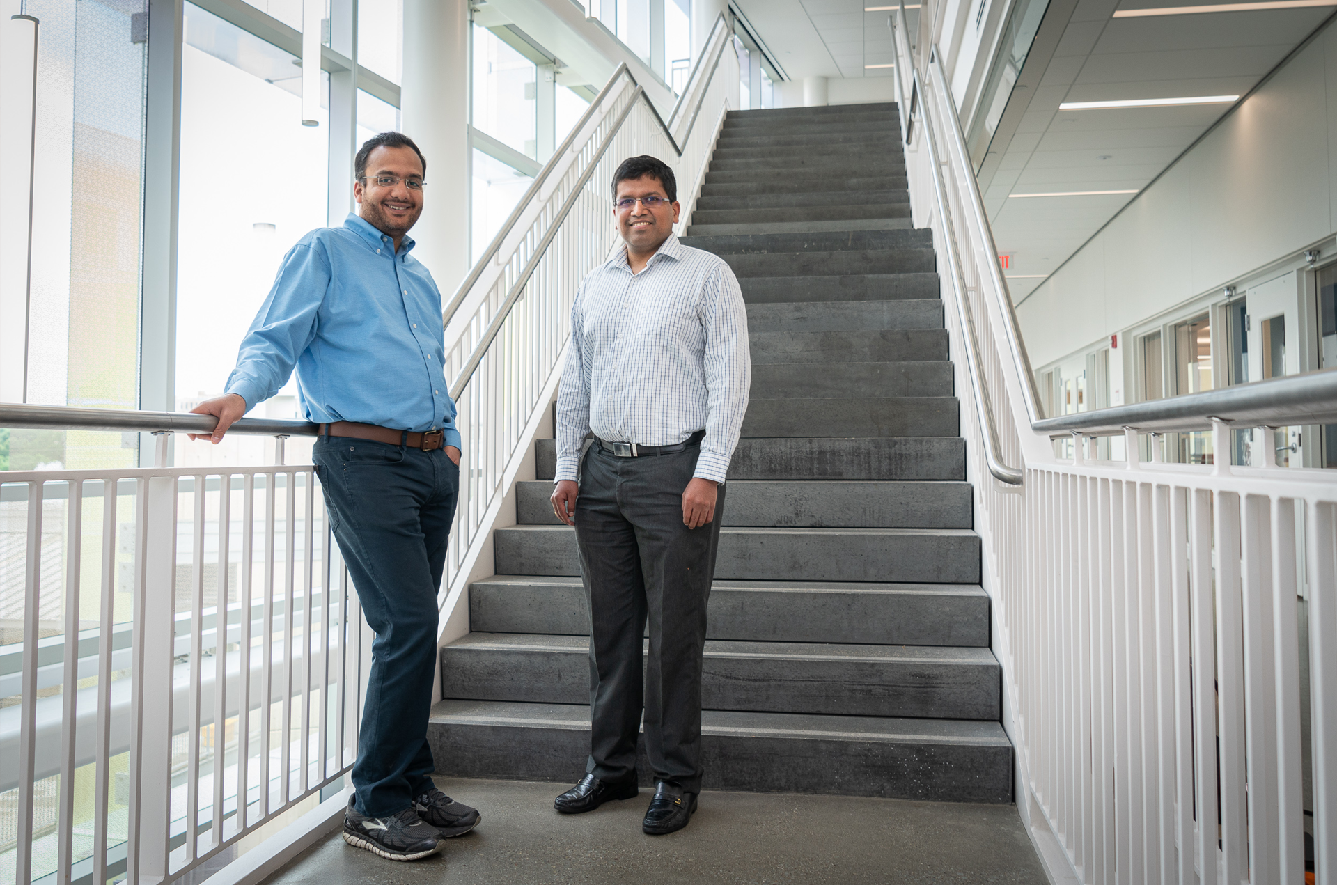 Two men, Rahul Panat and Vipul Goyal, standing in the stairway of Scott Hall on CMU's campus.