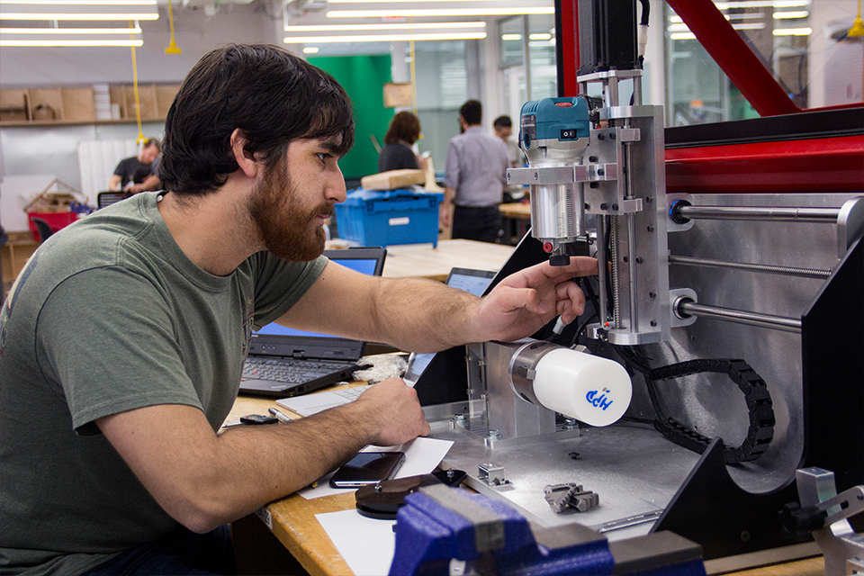Student in Tech Spark lab adjusting a machine