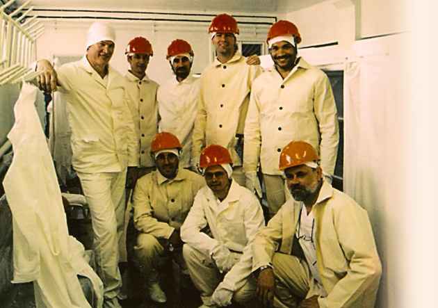 A group shot of seven men, all wearing white uniforms, in hardhats.