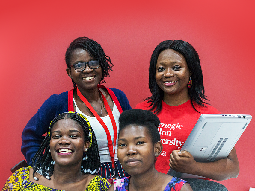 Photo of four female CMU-Africa students, one holding a laptop