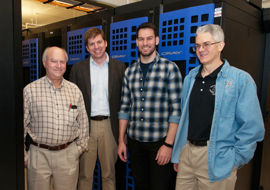 Four men posing with the supercomputer