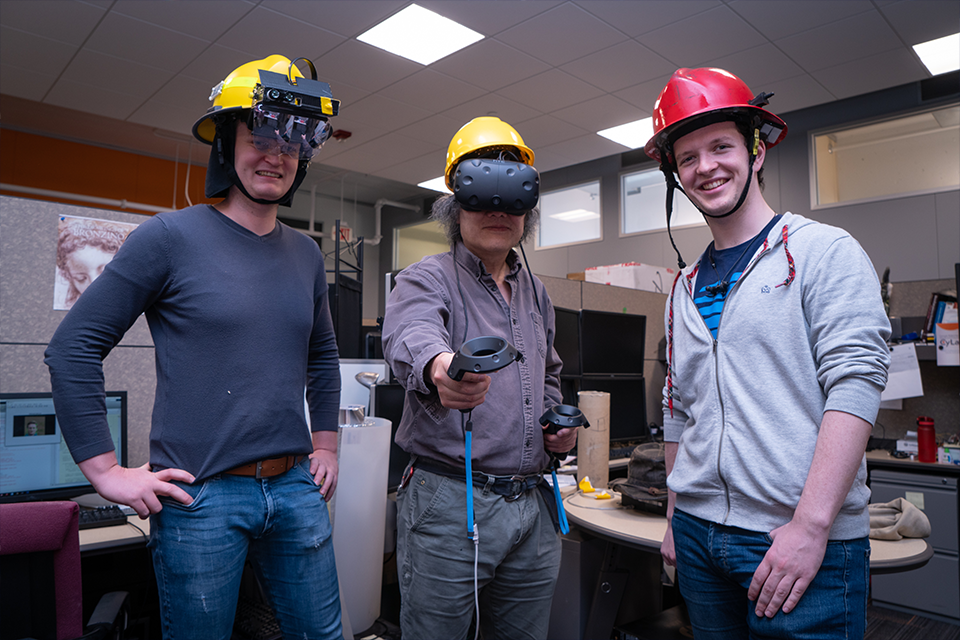 Three researchers in a lab wearing prototype helmets
